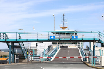 Ferry terminal with loading ramp and pedestrian bridge, showcasing maritime transportation and infrastructure in a coastal setting
