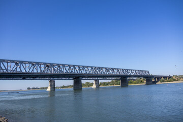 Large steel truss railway bridge crossing a wide river under a clear blue sky