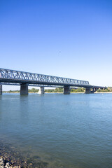 Large steel truss railway bridge crossing a wide river under a clear blue sky