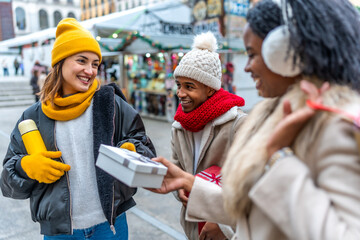 Friends exchanging christmas gifts at a winter market