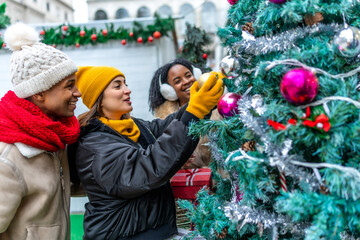 Friends decorating christmas tree at christmas market