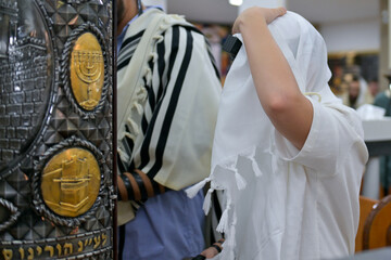 A bar mitzvah boy reading from the Torah scroll in a synagogue.