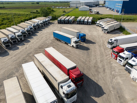 Fototapeta Aerial view of a large truck parking lot at a logistics hub, with multiple commercial semi trucks parked in organized rows