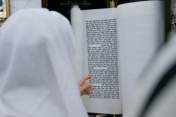 A bar mitzvah boy reading from the Torah scroll in a synagogue.