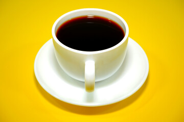 Closeup shot of a coffee cup with yellow background 