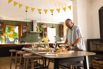 Senior couple preparing festive table in kitchen, enjoying celebration together