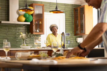 Senior couple enjoying wine and preparing meal together in modern kitchen