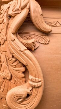 Detailed Terracotta Ornament Featuring Floral Carvings Against Textured Surface