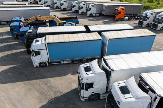 Fototapeta Aerial view of a large truck parking lot at a logistics hub, with multiple commercial semi trucks parked in organized rows
