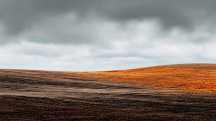 Obraz premium Rolling hills under a cloudy sky, with a gradient from brown to orange.