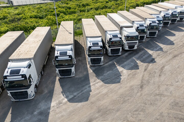 Aerial view of a large truck parking lot at a logistics hub, with multiple commercial semi trucks...
