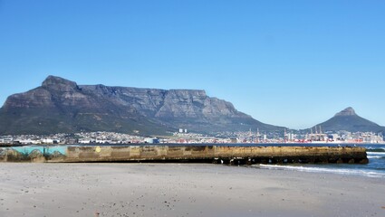 Naklejka premium Landscape with the beach and Table Mountain across the sea in morning light