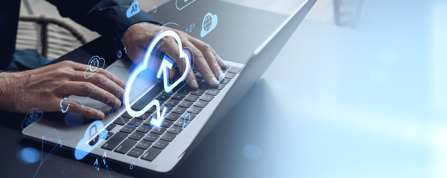 Hands typing on laptop with digital cloud and upload icons representing online data storage and cloud computing concept on light blue background.