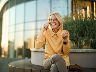 Portrait of a happy maturewoman posing, using a smartphone phone or taking a selfie photo outdoors...