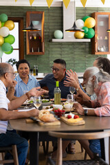 Senior friends enjoying lively conversation and meal together at home party