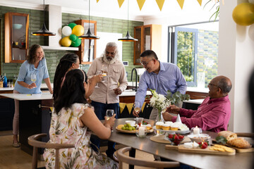 Senior friends enjoying drinks and conversation at home during festive party