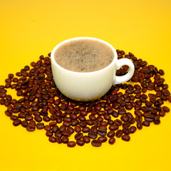 cup of coffee with beans closeup shot on yellow background close-up view 