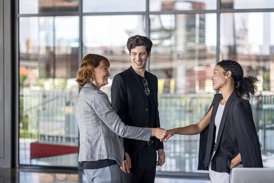 Business team from diverse cultures, genders, and generations celebrate the success hitting targets. Group of office workers express their appreciation to each other at the balcony. Cross generations - Powered by Adobe