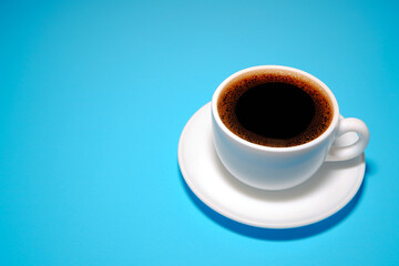 Coffee cup on blue background close-up view with copy space 