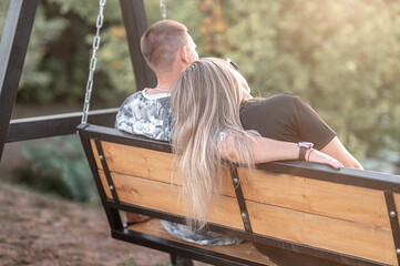 08/26/2025 Germany. A girl with long hair and a guy are sitting on a bench. In the sun during the day.