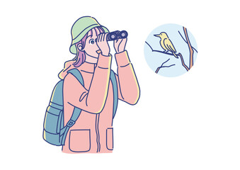 双眼鏡を持ってバードウォッチングをする若い女性