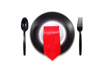 fork and knife with black plate red tie over on plate closeup view 
