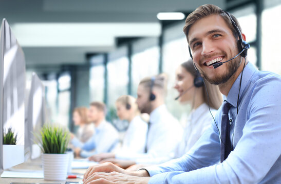 Portrait of call center worker accompanied by his team. Smiling customer support operator at work.