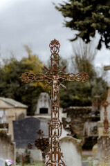 Obraz premium An ornate, rusty iron crucifix depicting Christ on the cross in an old cemetery on a cloudy day.