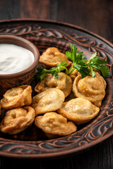 Close-up of fried dumplings with sour cream sauce on a rustic plate