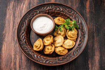 Fried dumplings with sour cream sauce on a rustic plate