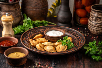 Fried dumplings with sour cream, ketchup, and mustard on a rustic table