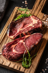 Dry aged beef ribeye steak on wooden board with salt and arugula