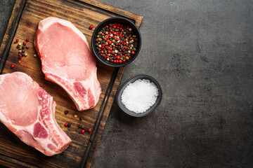Raw pork meat steaks with spices on cutting board. Flat lay with copy space.