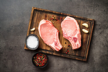 Raw pork meat steaks on cutting board. Flat lay with copy space.