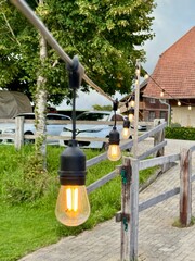 Warm Outdoor String Lights Along a Wooden Fence in Countryside
