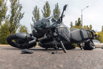 The motorcycle lies on the sidewalk after a ride. Serious accident. Accident, close-up. Lost control and fell. Driving hazards. Collisions with another vehicle.