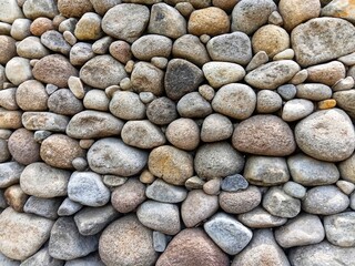 Stone wall background made of natural river rocks, perfect for construction, landscaping, and texture design. Rustic stone pattern for architecture and outdoor decoration.