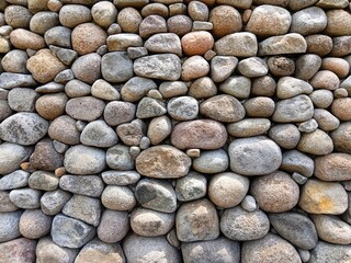 Stone wall background made of natural river rocks, perfect for construction, landscaping, and texture design. Rustic stone pattern for architecture and outdoor decoration.