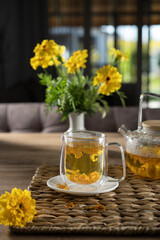 Refreshing herbal tea with vibrant yellow flowers on a wooden table under soft natural light