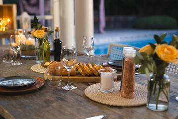 Elegant outdoor dining setup with wine glasses and bread by poolside