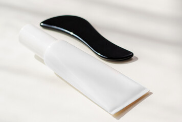 Gua sha tool and skincare cream displayed in a serene bathroom setting for wellness and beauty rituals