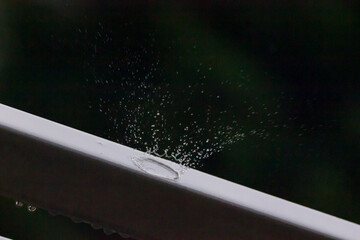 Water splash drops during a rain storm, background is dark and blurred.
