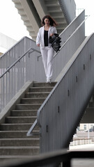 A fit woman descends the stairs in a contemporary urban setting, holding her workout gear. The balance between motion and stillness reflects the dynamic rhythm of modern active lifestyles.