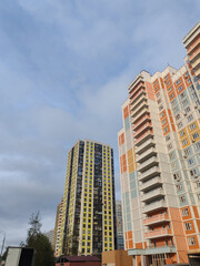 A towering residential building with pastel accents, featuring a wide array of windows and balconies. The design reflects the contemporary urban approach to high-density living in city environments.