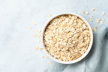 Rolled oats flakes in a wooden bowl with ears. Top view with copy space on white background.