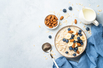 Oatmeal porridge with milk, bananas and blueberries. Top view.