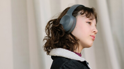 A calm young girl with headphones lowers her gaze, lost in thought. This image explores themes of contemplation, emotional depth, and the power of auditory experiences.