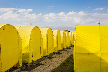 alpine camp with yellow tents in the base camp in front of the big peak of the mountain, preparation of climbers for the ascent to avoid the death of climbers without acclimatization