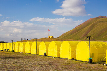 alpine camp with yellow tents in the base camp in front of the big peak of the mountain, preparation of climbers for the ascent to avoid the death of climbers without acclimatization