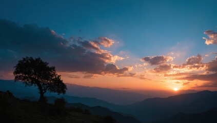 Obraz premium Panoramic sunset over mountains with a solitary tree